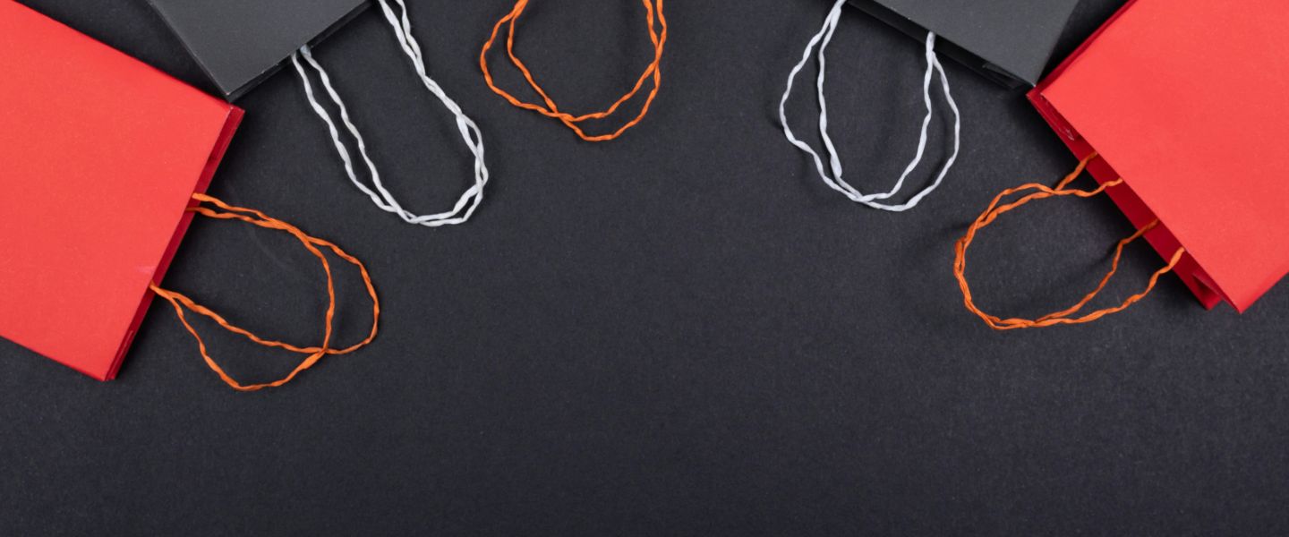 Black and red paper shopping bags arranged in a curve on a black background
