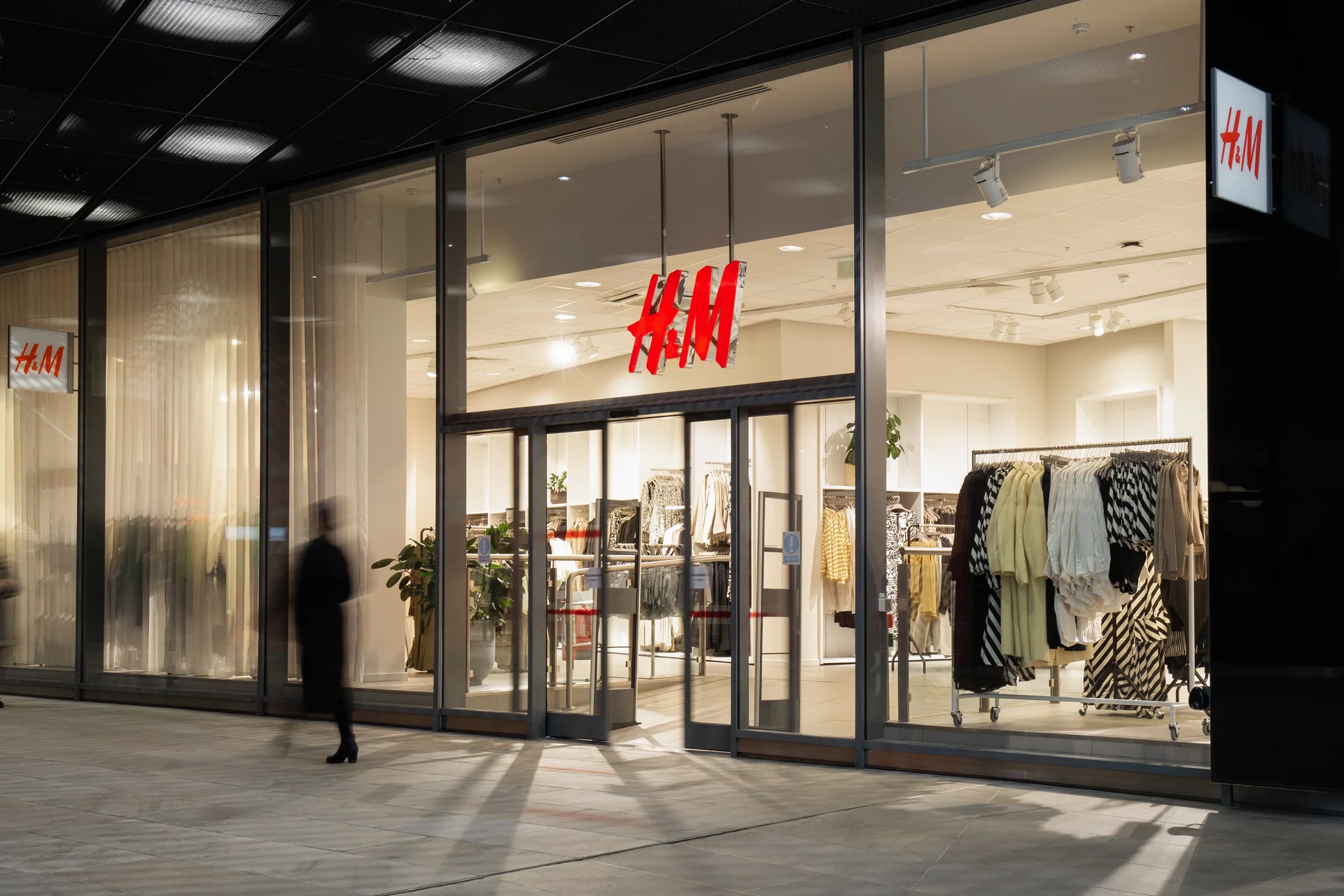 H&M clothing store front with glass windows and illuminated sign