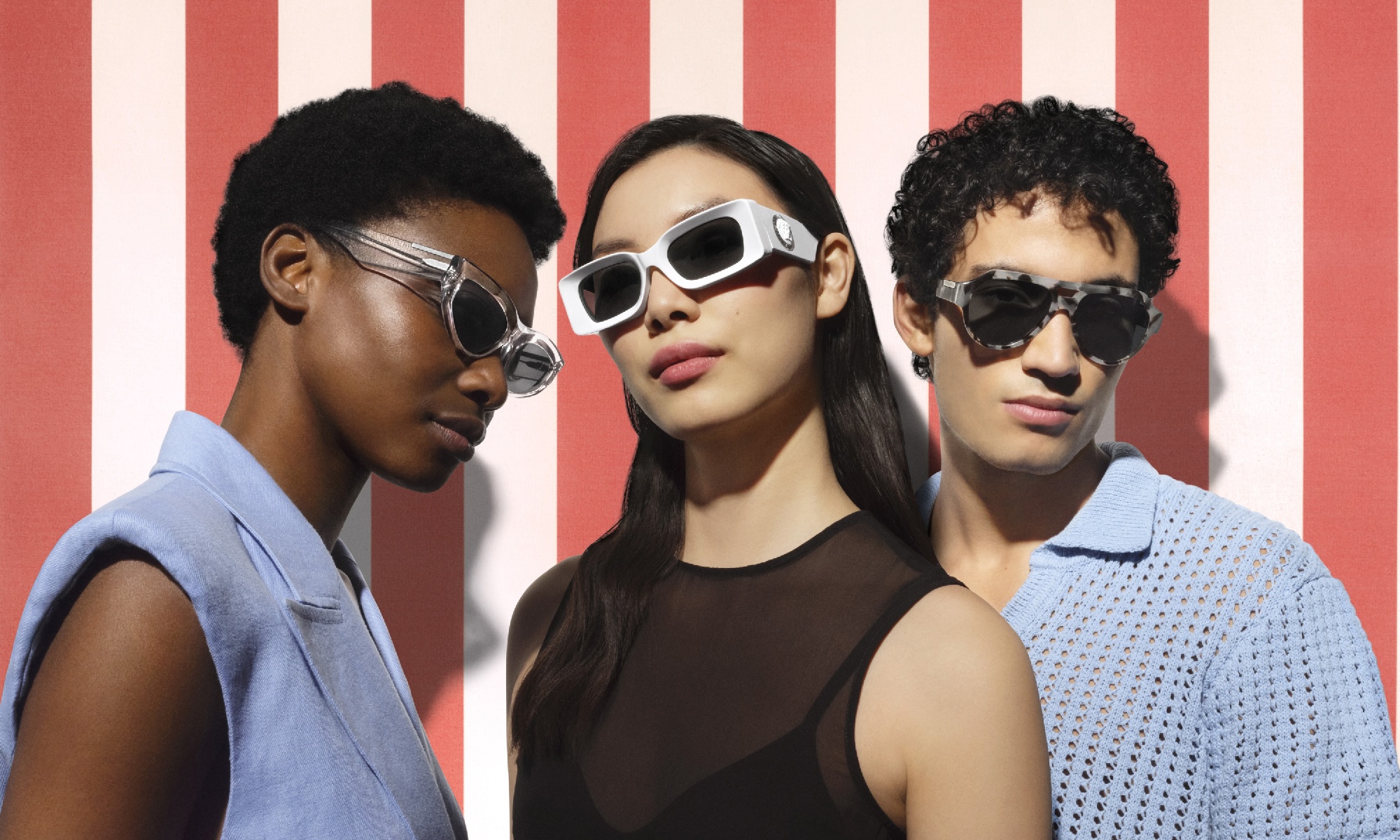 Three people wearing sunglasses against a red and pink stripe background