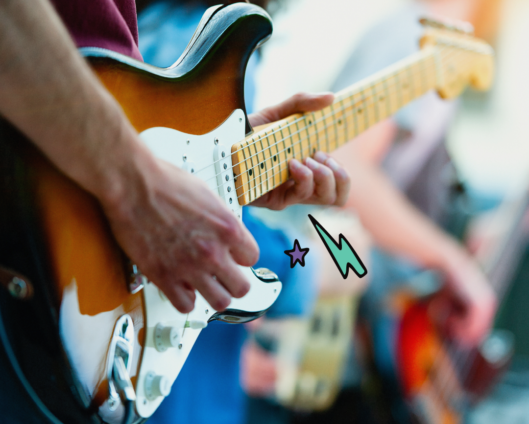 Close-up of a person's hand playing guitar outdoors