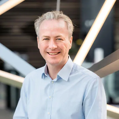 Man in light blue shirt smiling in modern interior.