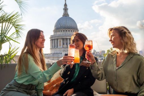 Women raising glasses on Madison rooftop with a view of St Paul's Cathedral