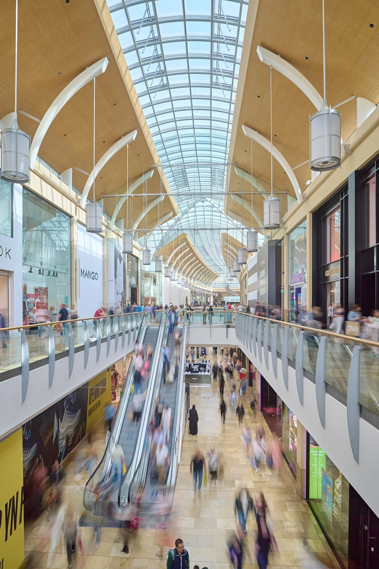 Vertical shot of St David's mall levels. Shows escalators, Mango, Adidas, and a modern, arched glass roof.