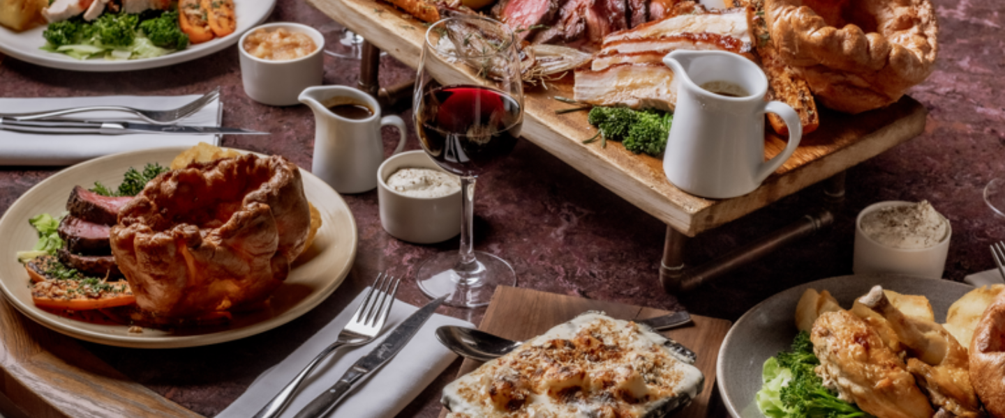 Table spread of roast dinners with Yorkshire puddings, vegetables, gravy and red wine.