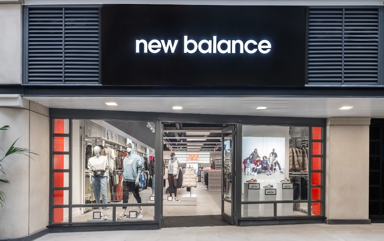 New Balance store front with doors open and mannequins wearing sports clothing in the windows