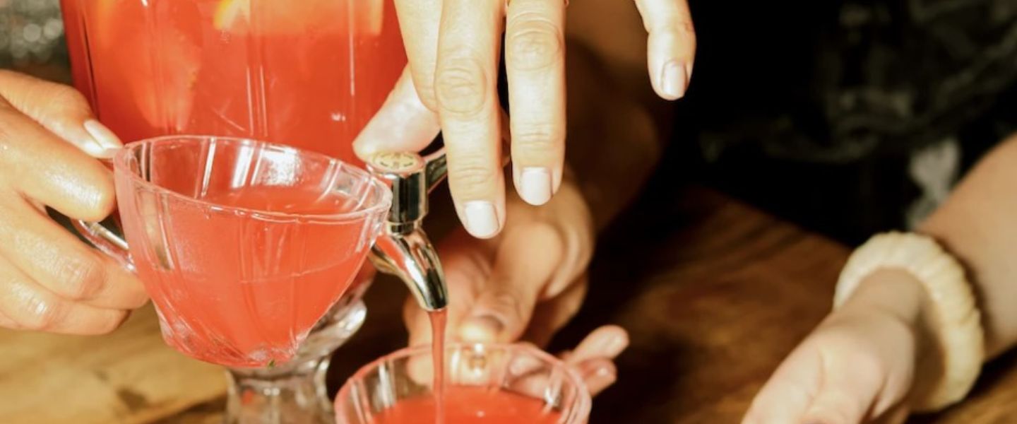 Cocktails being poured into teacups from a glass jug