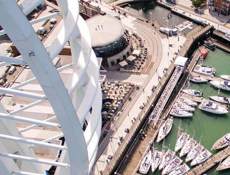Marina with boats docked, next to modern waterfront architecture.
