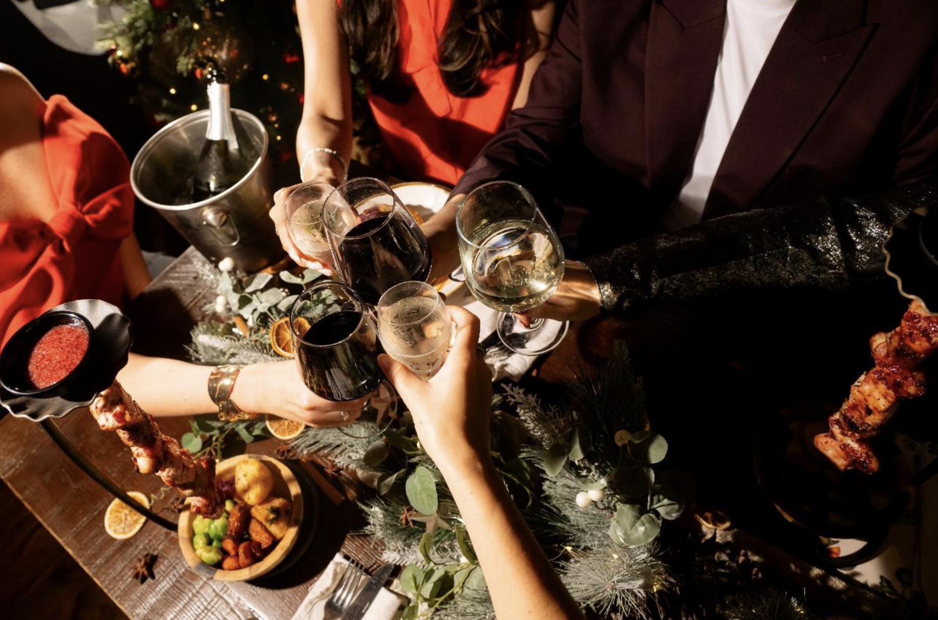 Hands toast wine glasses over a festive table