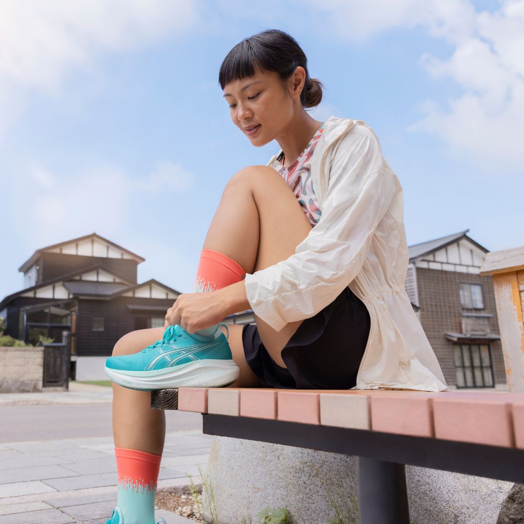 A runner putting on a pair of ASICS Gel-Nimbus 27 running shoes