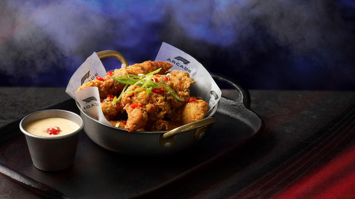Salt and pepper chicken in a black bowl with an F1 Arcade wrapper