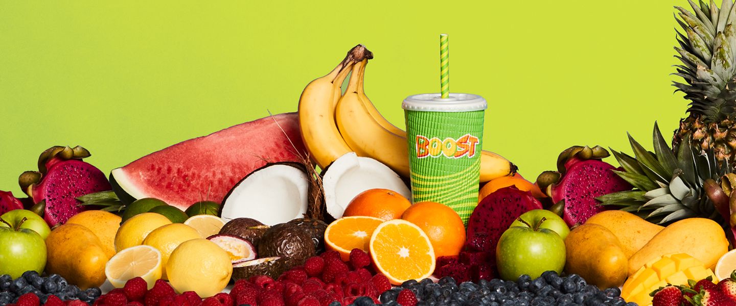 A selection of fruits surrounding a Boost smoothie
