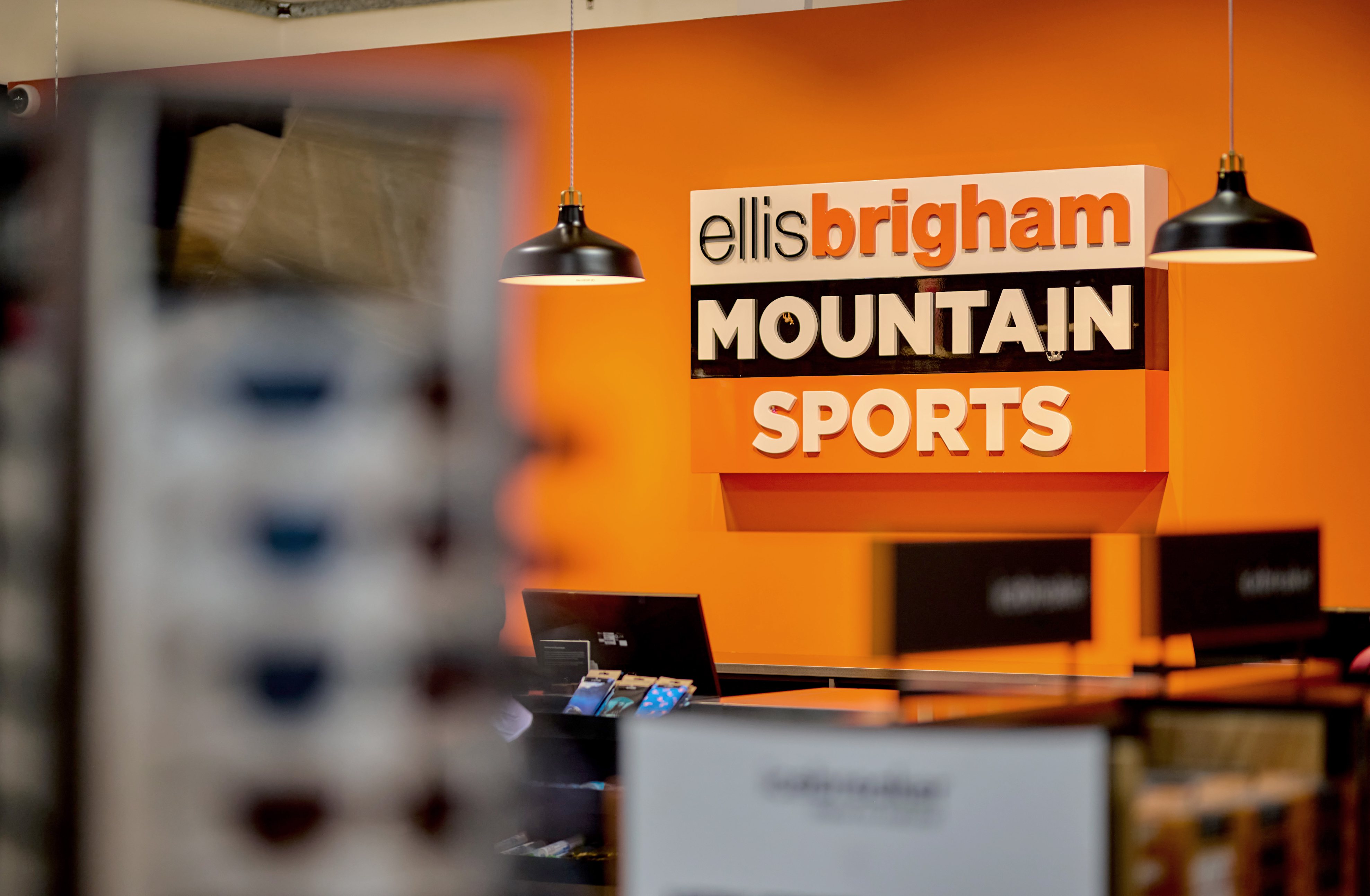 Photo of an Ellis Brigham logo in a store against an orange wall