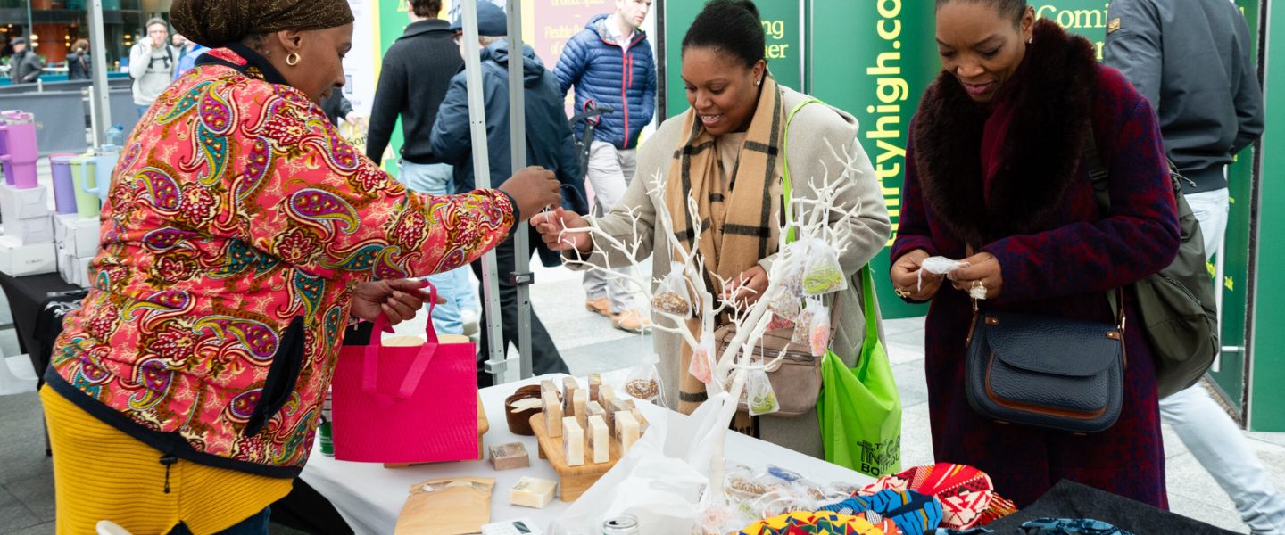 Three women shopping at a stall at a pop-up market