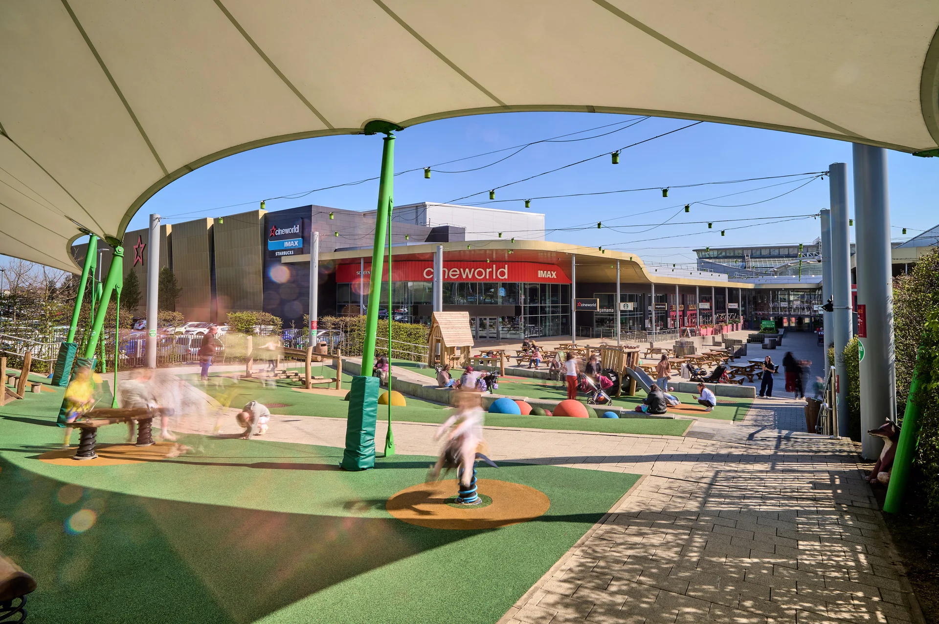 Exterior view of the outdoor leisure space at **White Rose Shopping Centre**, showing the children's **play area** with play equipment and seating, covered by a white canopy, with the **Cineworld IMAX** cinema visible in the background.