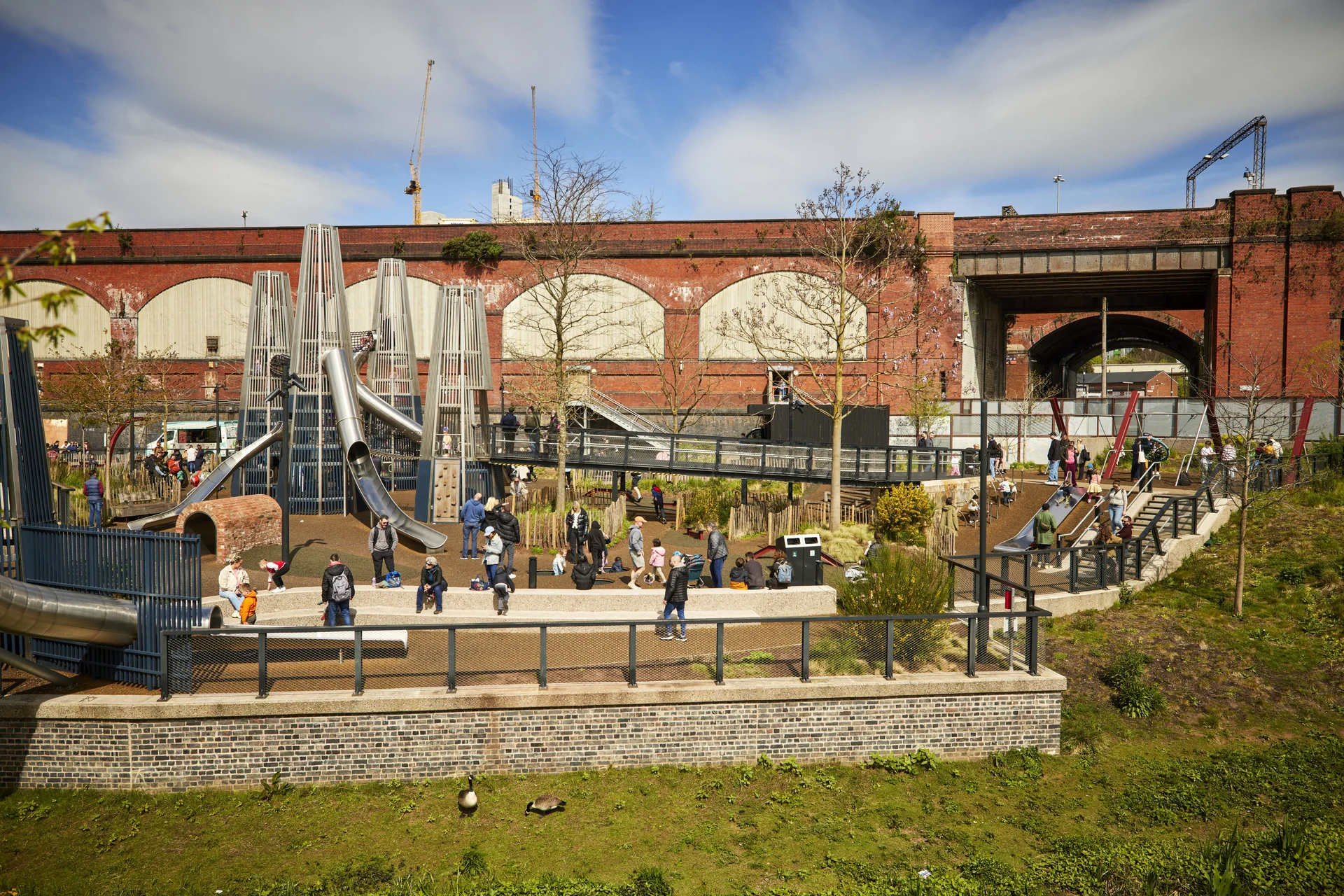Modern playground with slides and families enjoying outdoor activities.
