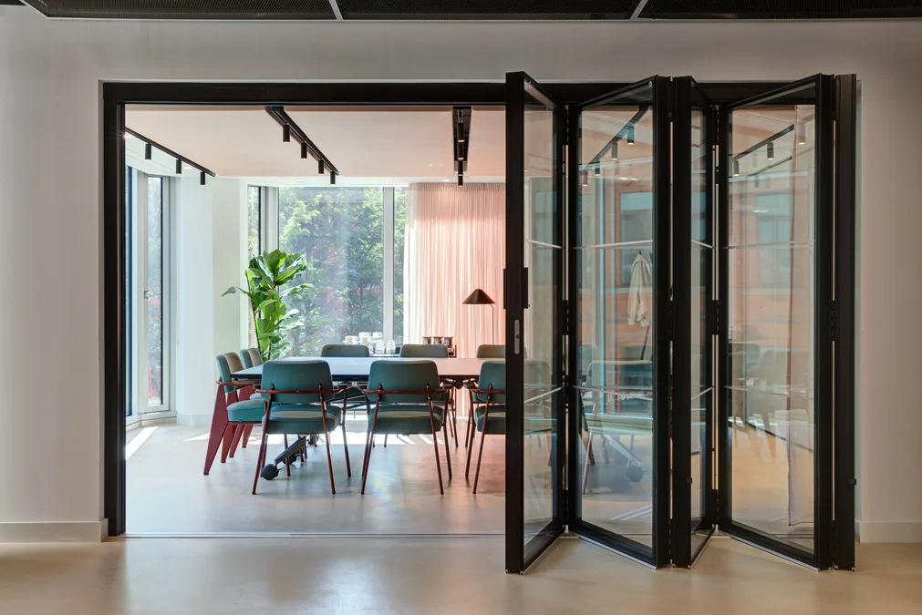 Glass meeting room with conference table and green chairs