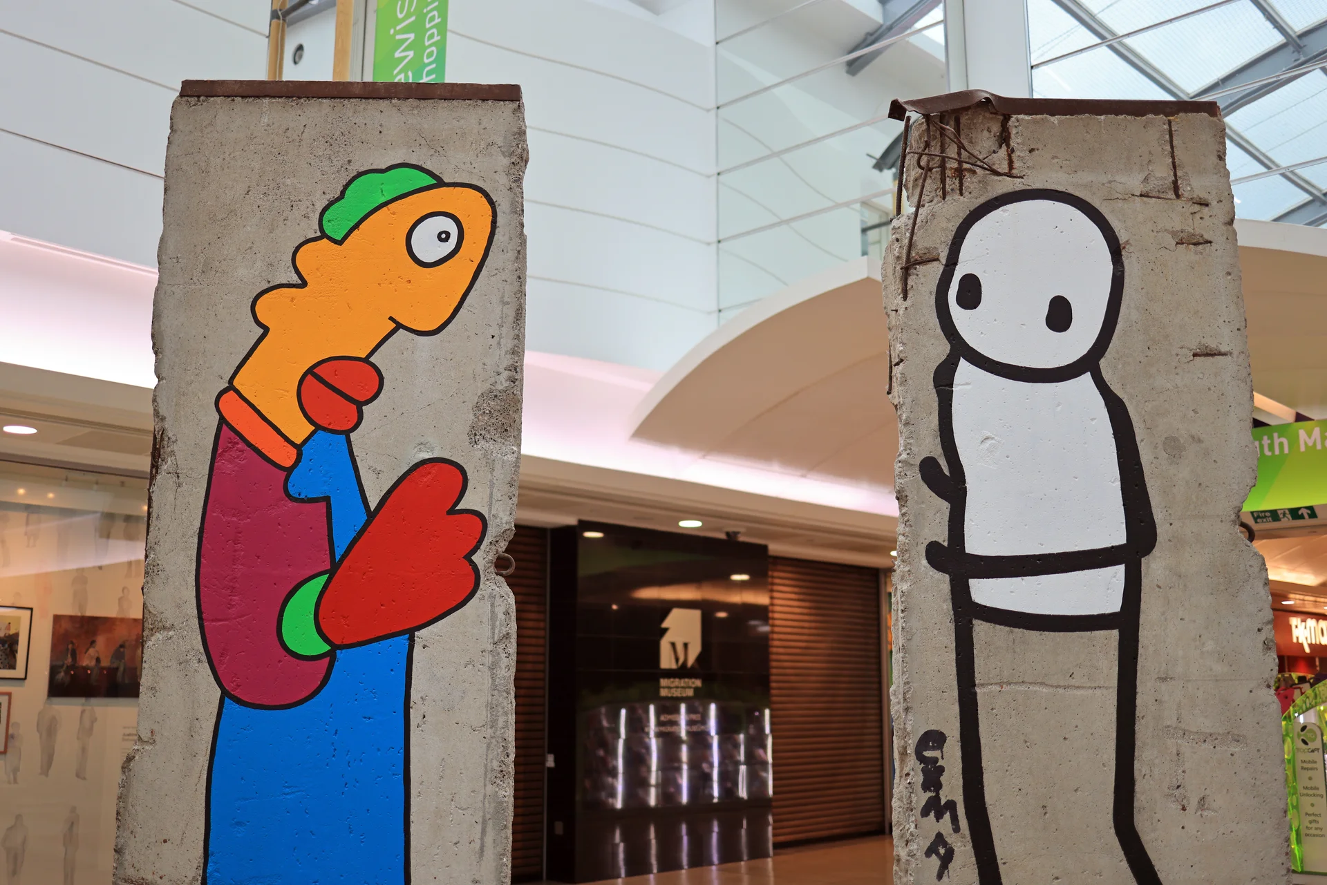 Berlin Wall segments with street art characters on display inside Lewisham Shopping Centre, near the Migration Museum.