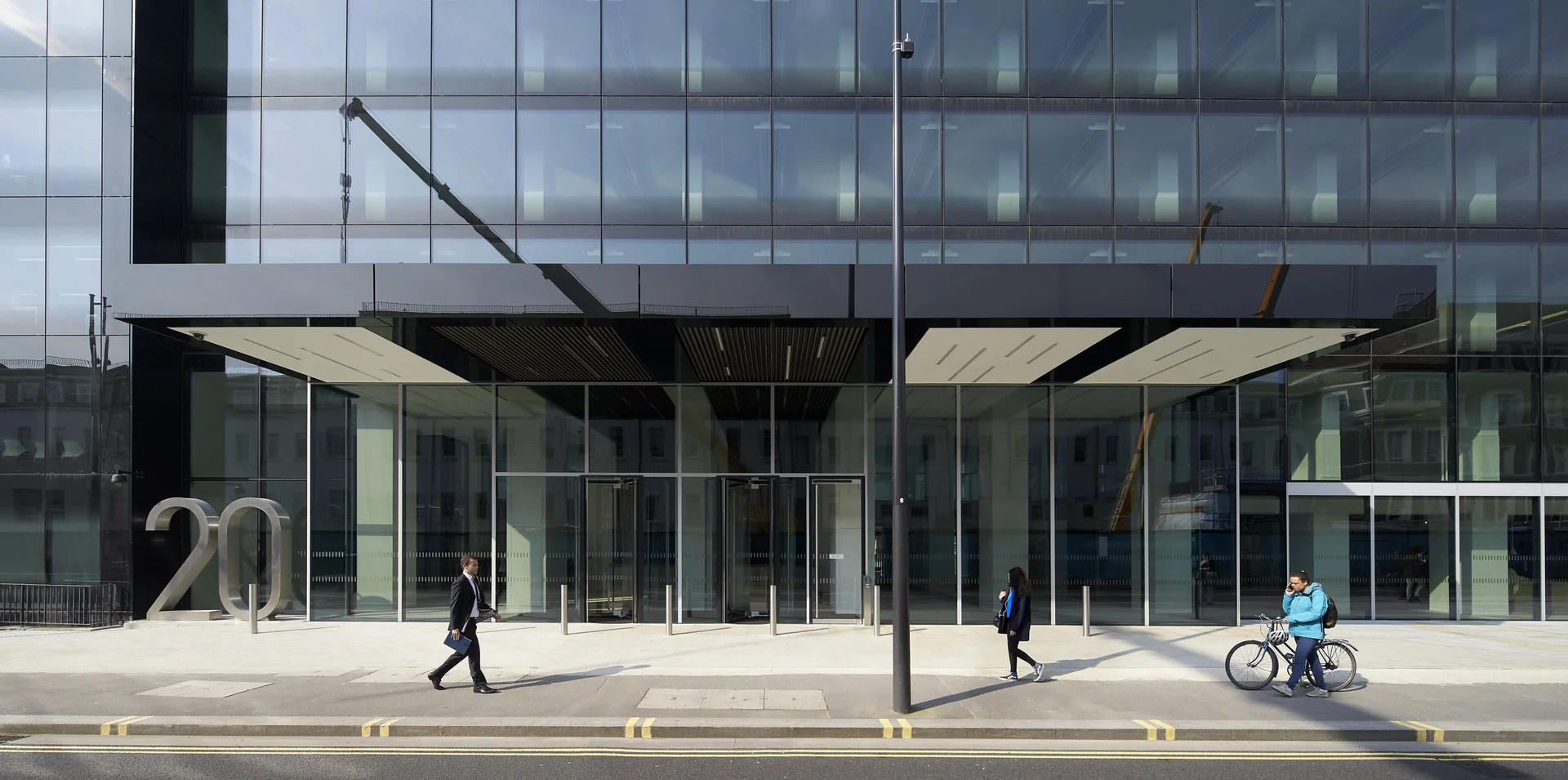 Glass office building entrance with people and bike racks