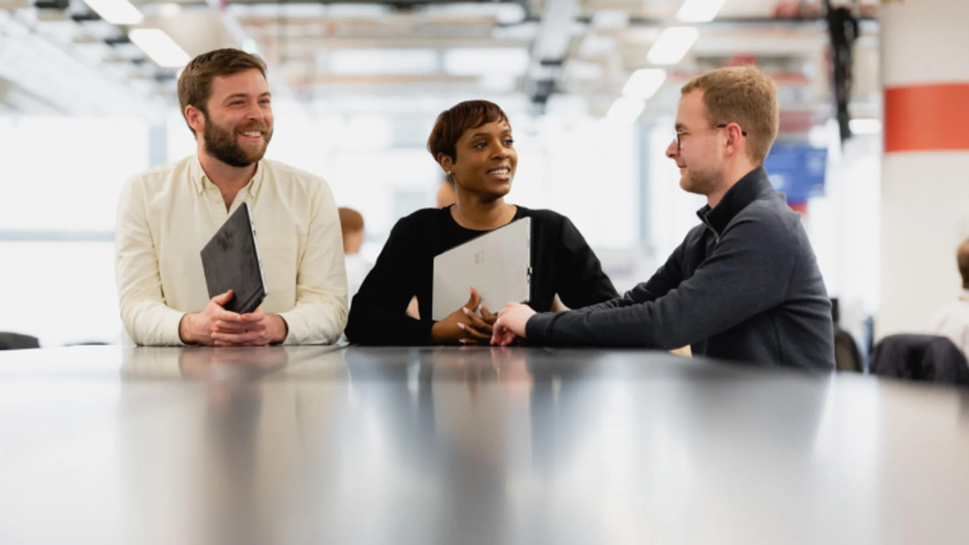 Three people having a business discussion around a table.
