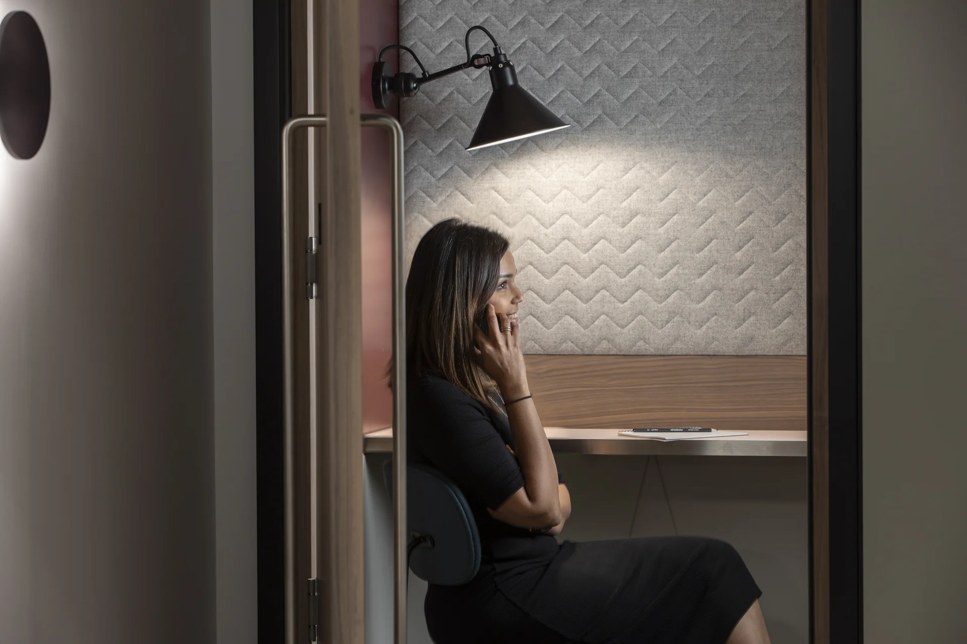 Private workspace with a woman using a phone in an acoustic booth
