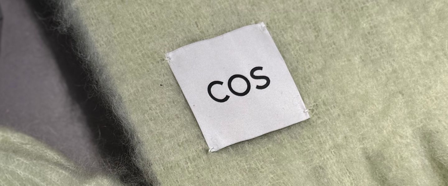 A COS label on a light green cashmere scarf