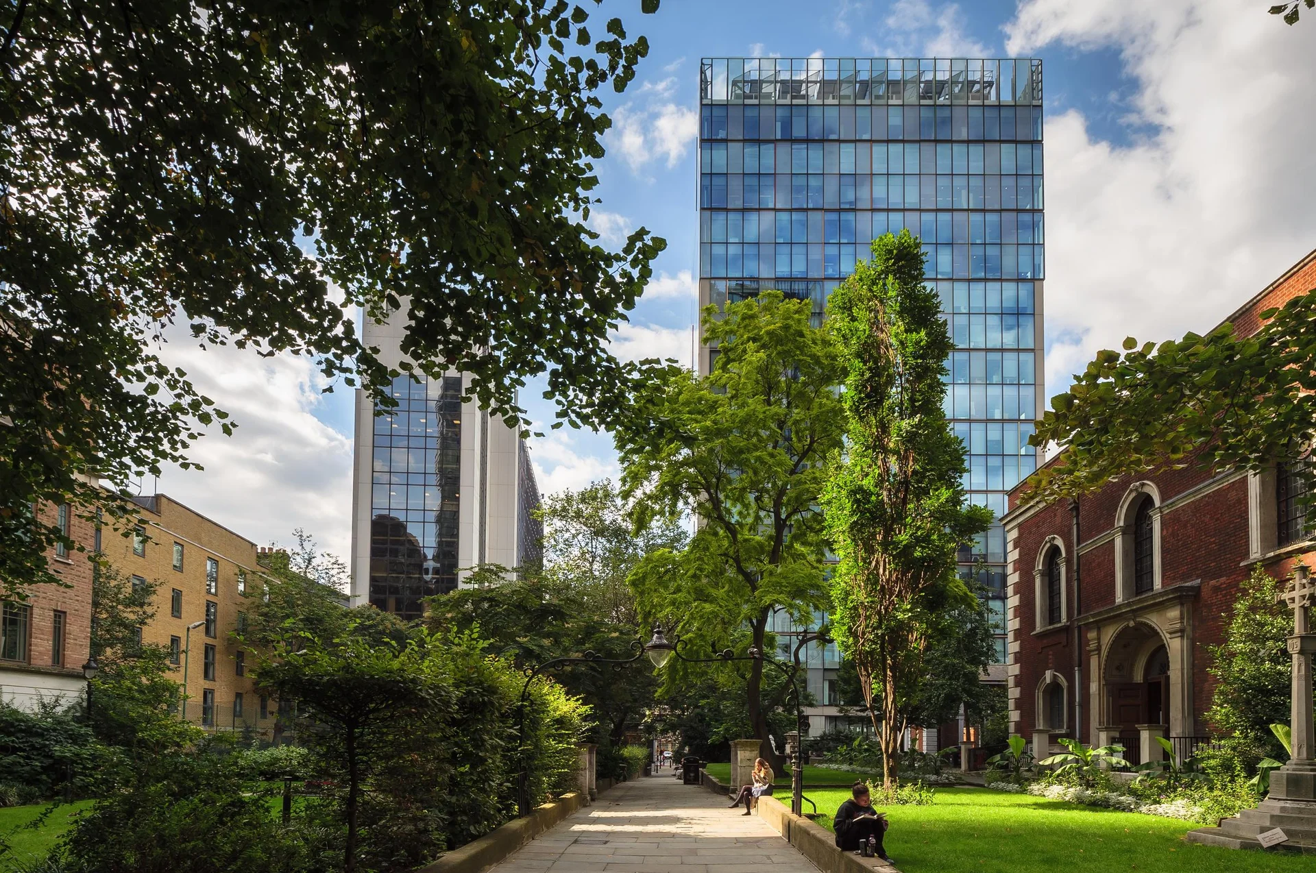 Modern glass building seen through lush greenery and city park