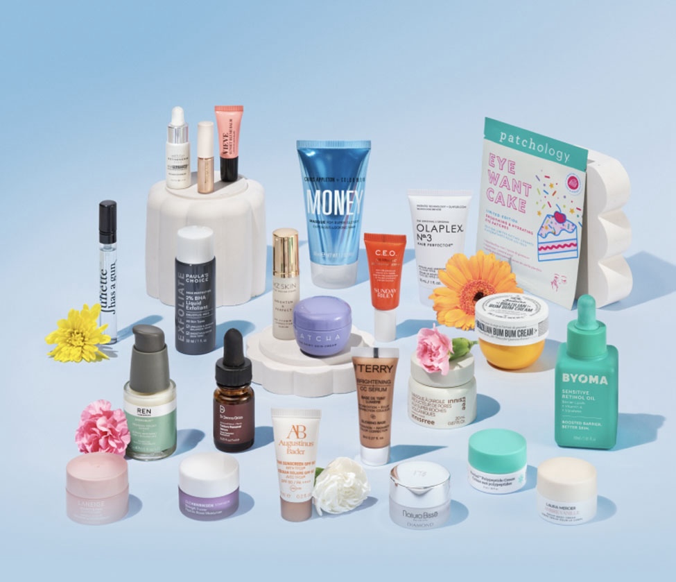 A collection of Space NK beauty products, displayed on a smooth blue gradient surface.