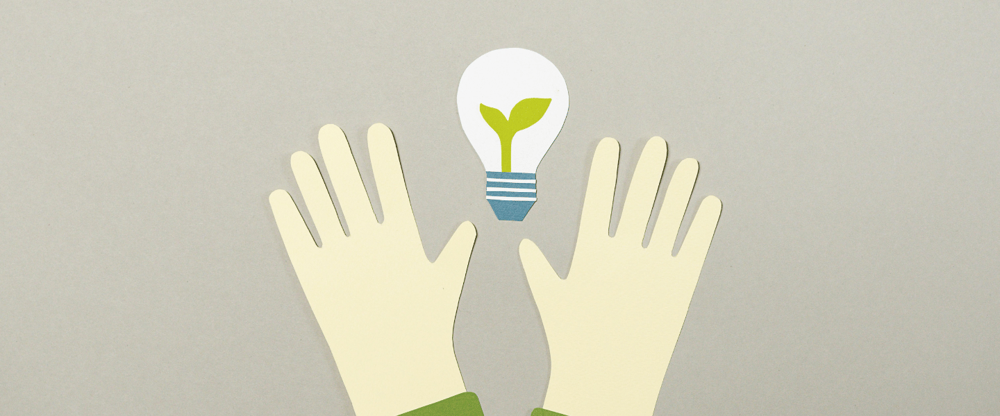 Paper hands holding out a paper lightbulb with a green plant inside it